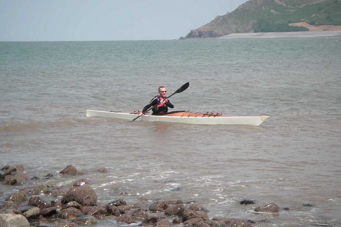 Home made wooden sea kayak near rocks